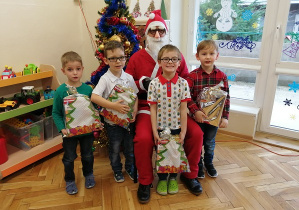 chłopcy stoją z Mikołajem i prezentami